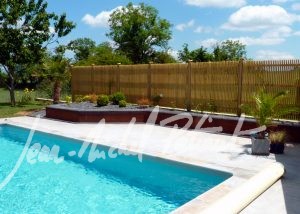 Piscine cachée derrière un claustra en bois