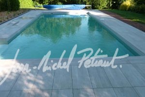 Piscine dans un jardin avec bord en dalles